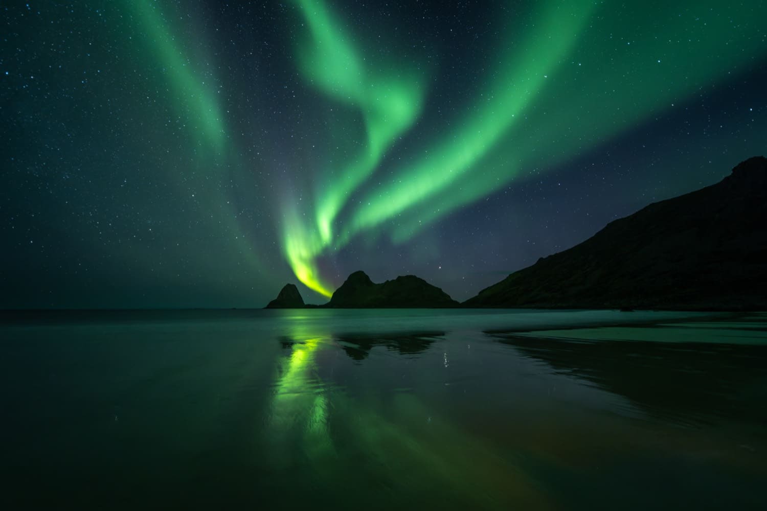 Green aurora corona swirling above a dark tarn and autumn shoreline